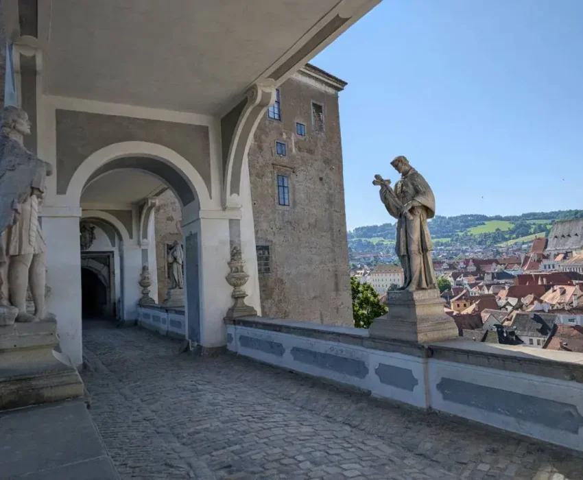 Crossing the castle bridge with baroque statues and views over the town